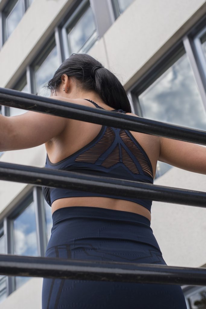backside girl wearing activewear bra top standing at gym