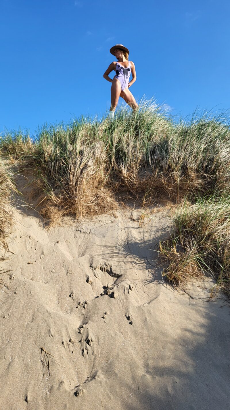 Woman standing in dunes wearing activewear bodysuit of Nanette Lindeman