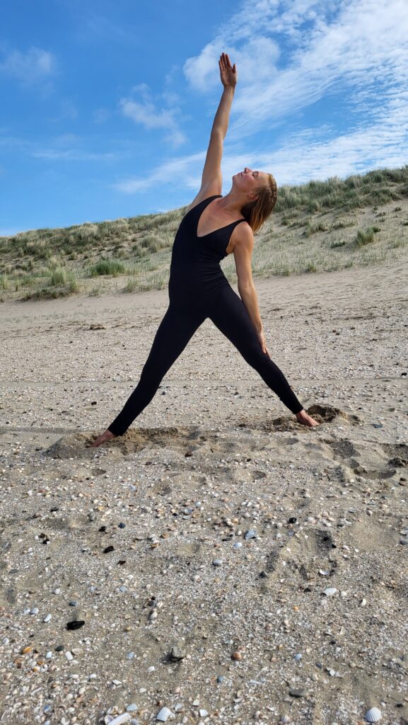 Woman in activewear of Nanette Lindeman in yoga pose at the beach