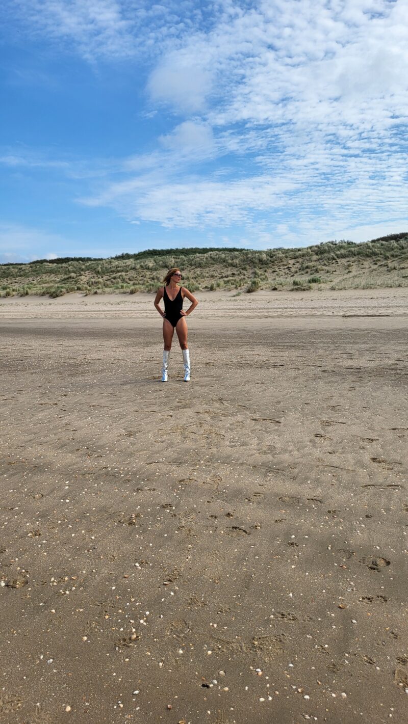 Woman standing at the beach wearing black bodysuit of Nanette Lindeman